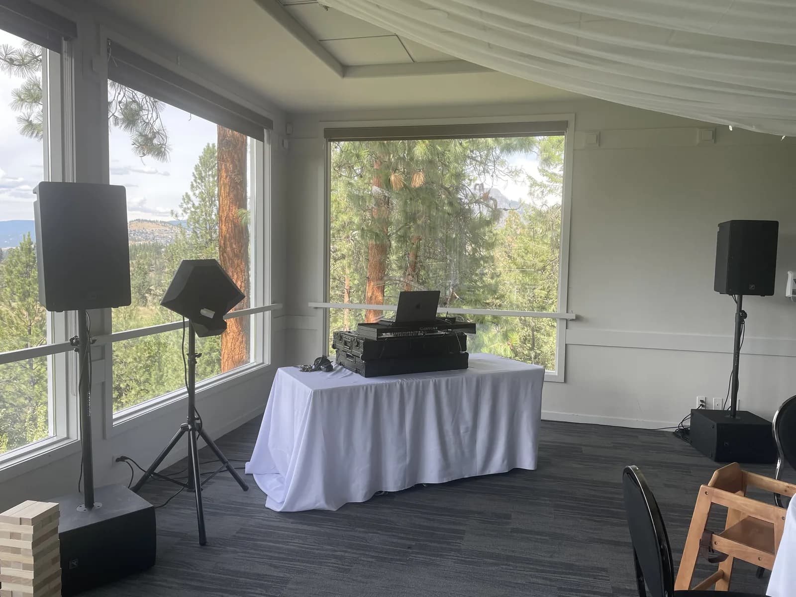 Clean wedding DJ setup with speakers, table, and gear placed in a bright event room