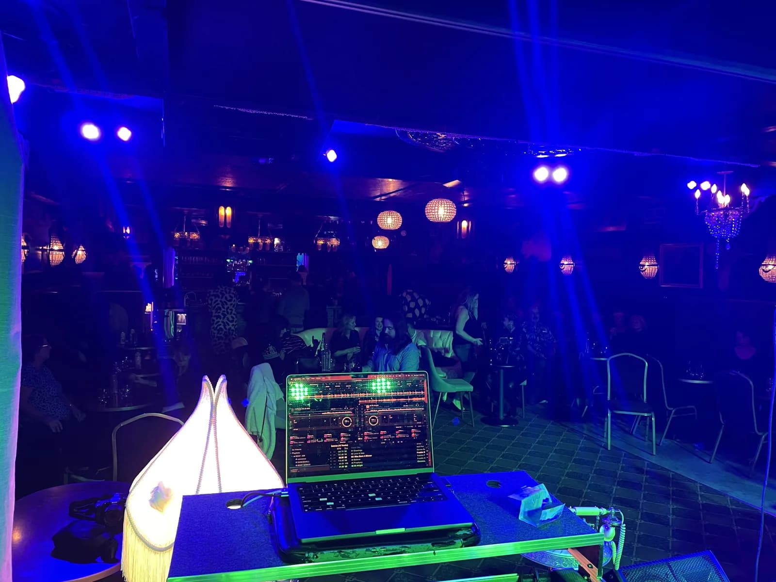 DJ booth view of a blue-lit dance floor with party lighting