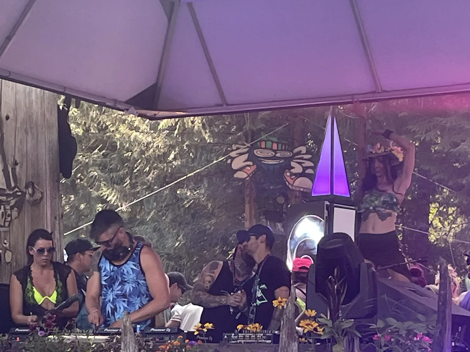 Outdoor party DJ setup with people gathered around the booth